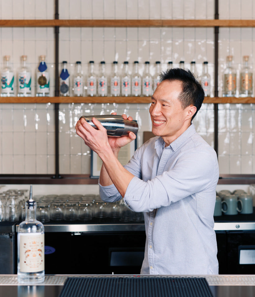 Bartender holding a cocktail shaker with custom Soil & Oak shelves in the background.
