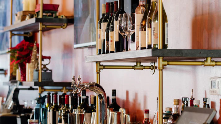Bar shelves built by Soil & Oak with bottles, glasses, and a mixer on a metal shelf.