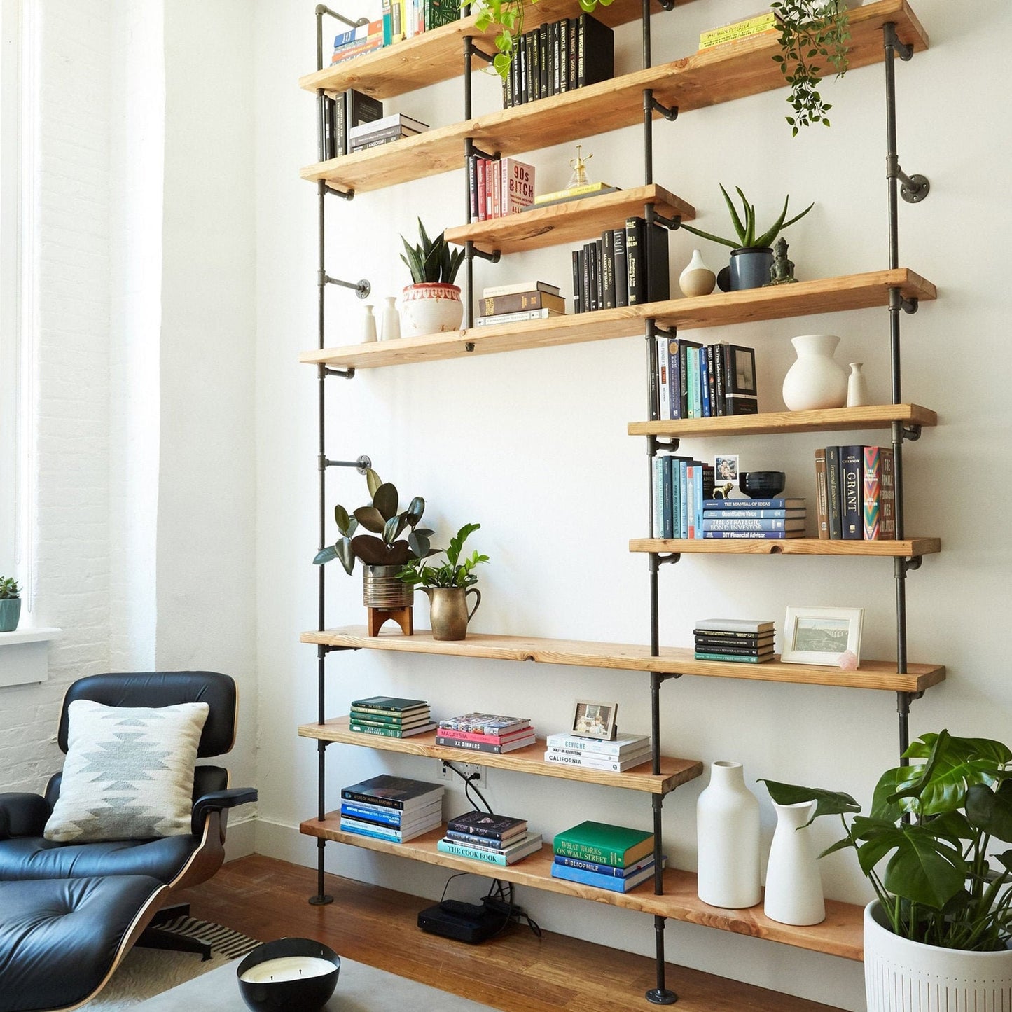custom bookshelf with back pipes and oak shelves in apartment living room | Soil & Oak