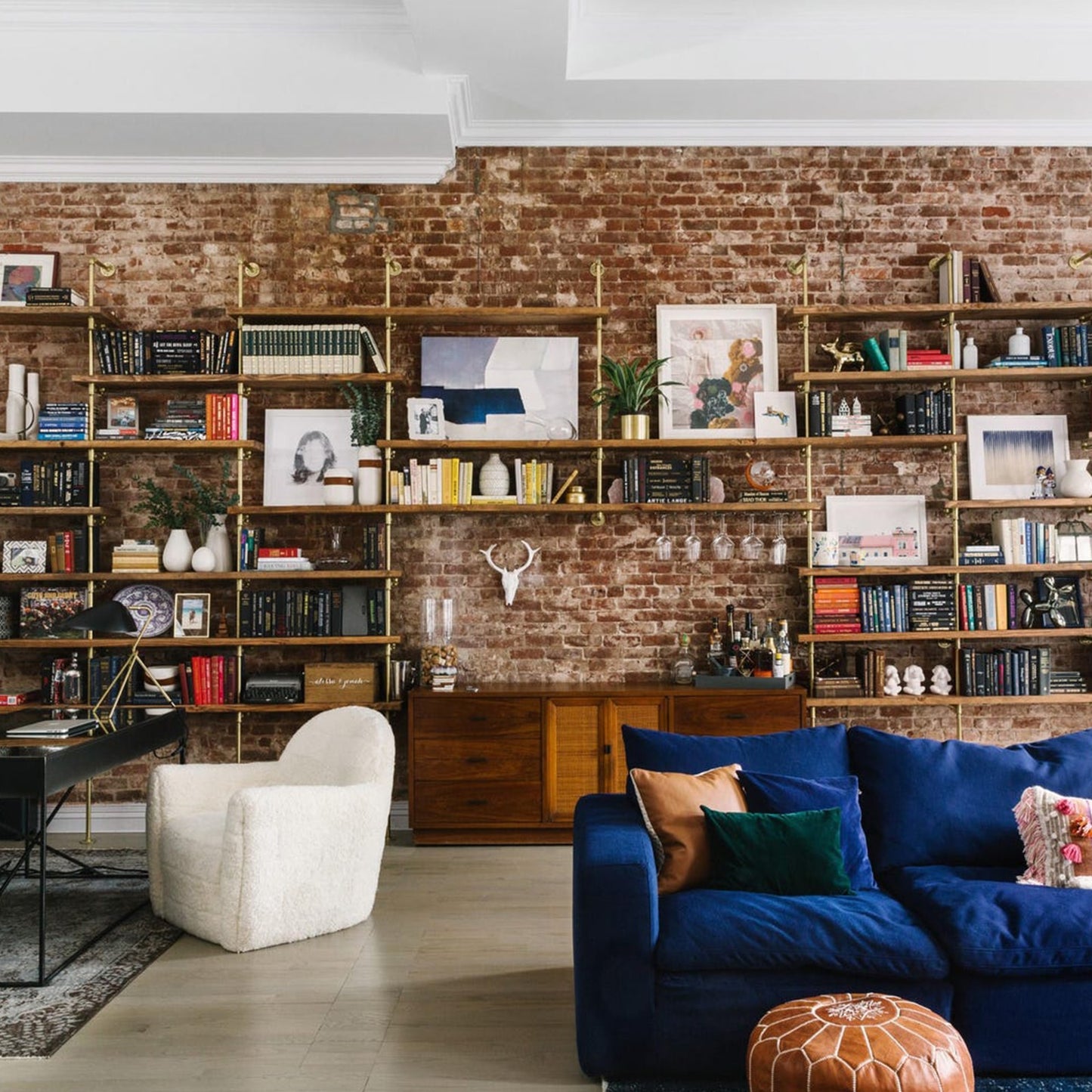 custom bookshelf with brass plated pipes and oak shelves in large living room with blue couch | Soil & Oak