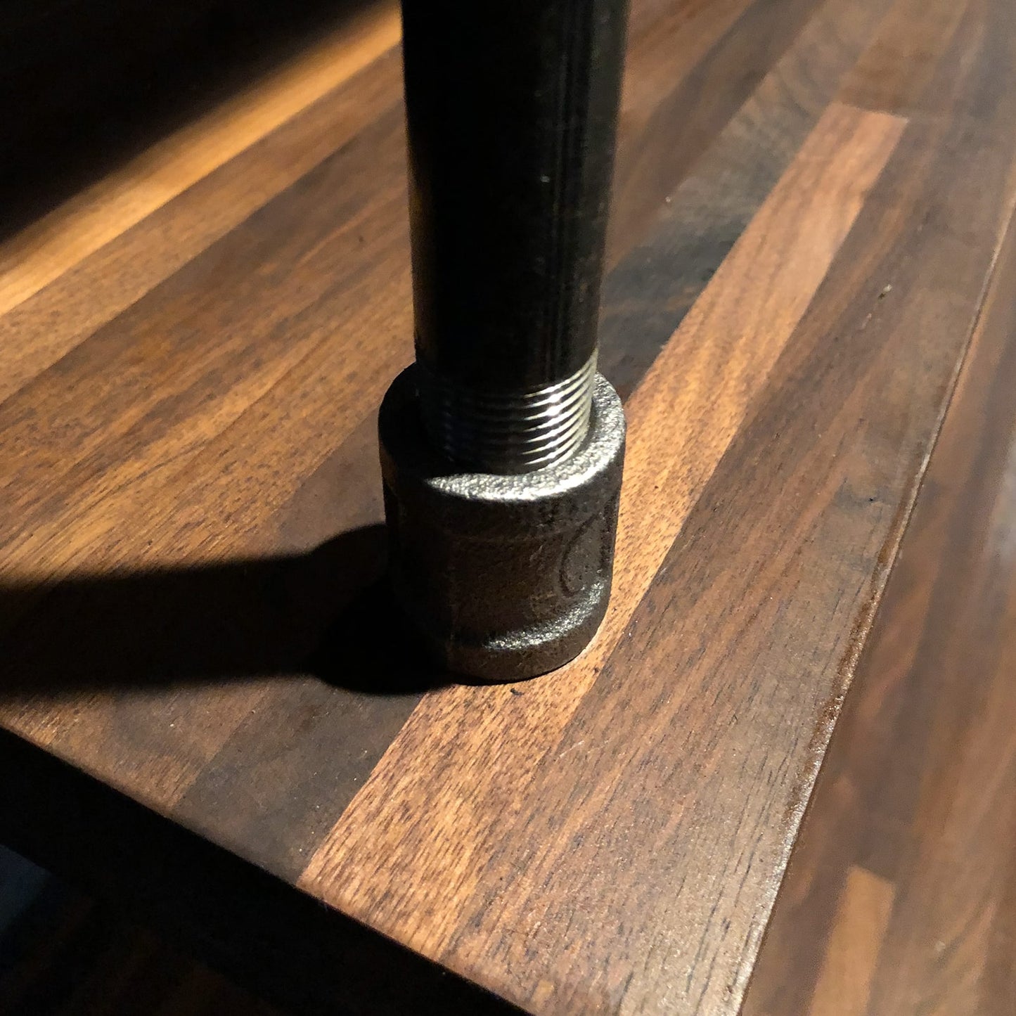Close up of black steel pipe connecting to an American walnut butcher block | Soil & Oak built-in desk table top