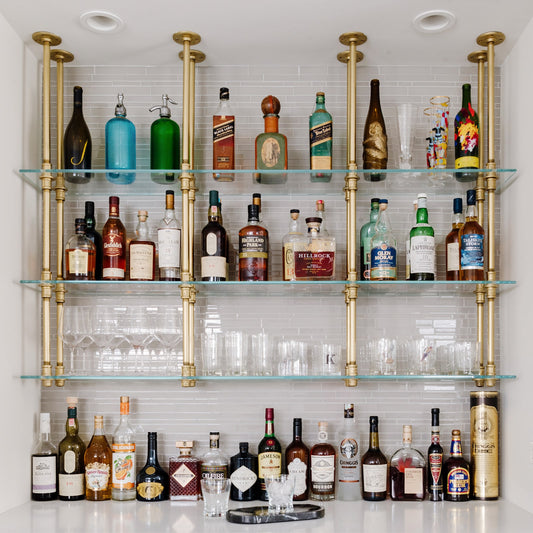 Ceiling mounted glass shelves with brass plated pipes in white tiled bar | Soil & Oak