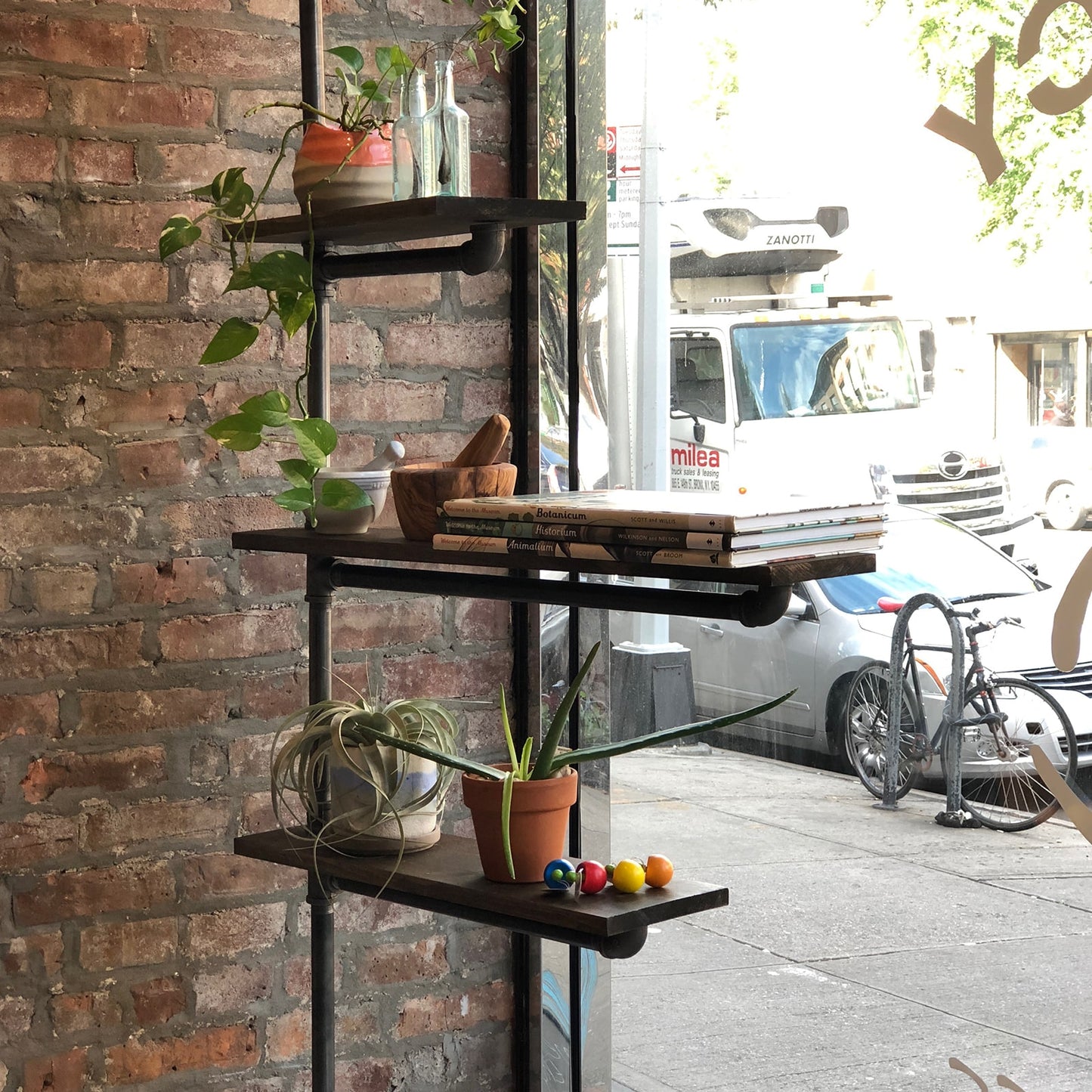 custom bookshelf with black pipes and dark stained wood shelves used in a brick and mortar display | Soil & Oak