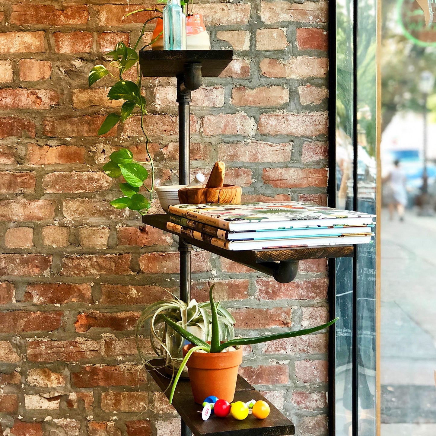 custom bookshelf with black pipes and dark stained wood shelves used in a brick and mortar display | Soil & Oak