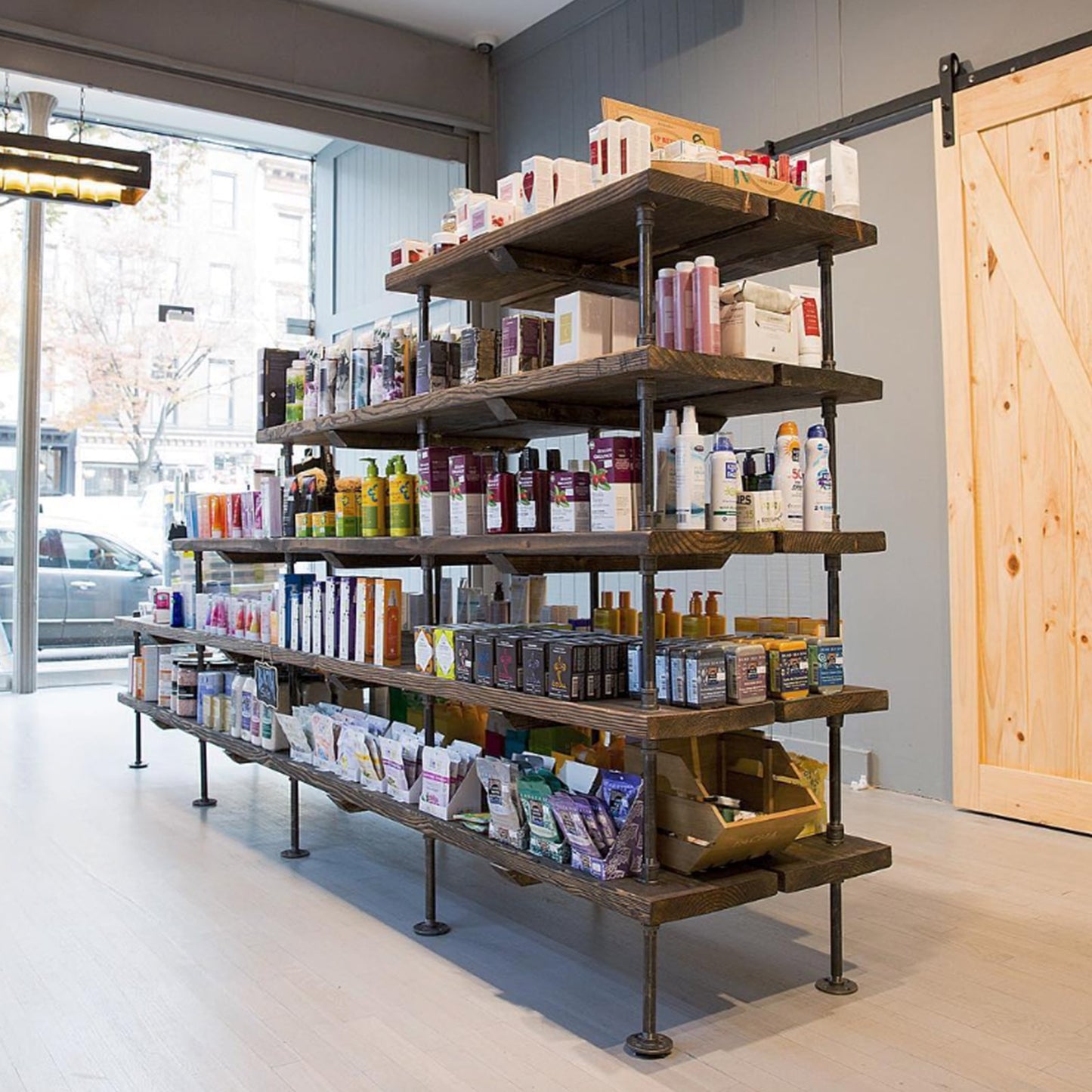 custom standalone bookshelf with black pipes and dark stained wood shelves used in a brick and mortar pharmacy | Soil & Oak