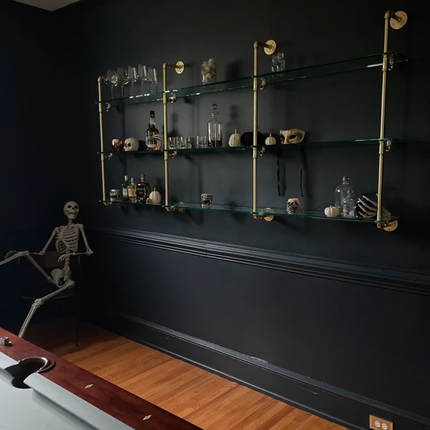 Wall mounted shelving with brass plated pipes and glass shelves in billiards room with black walls | Soil & Oak