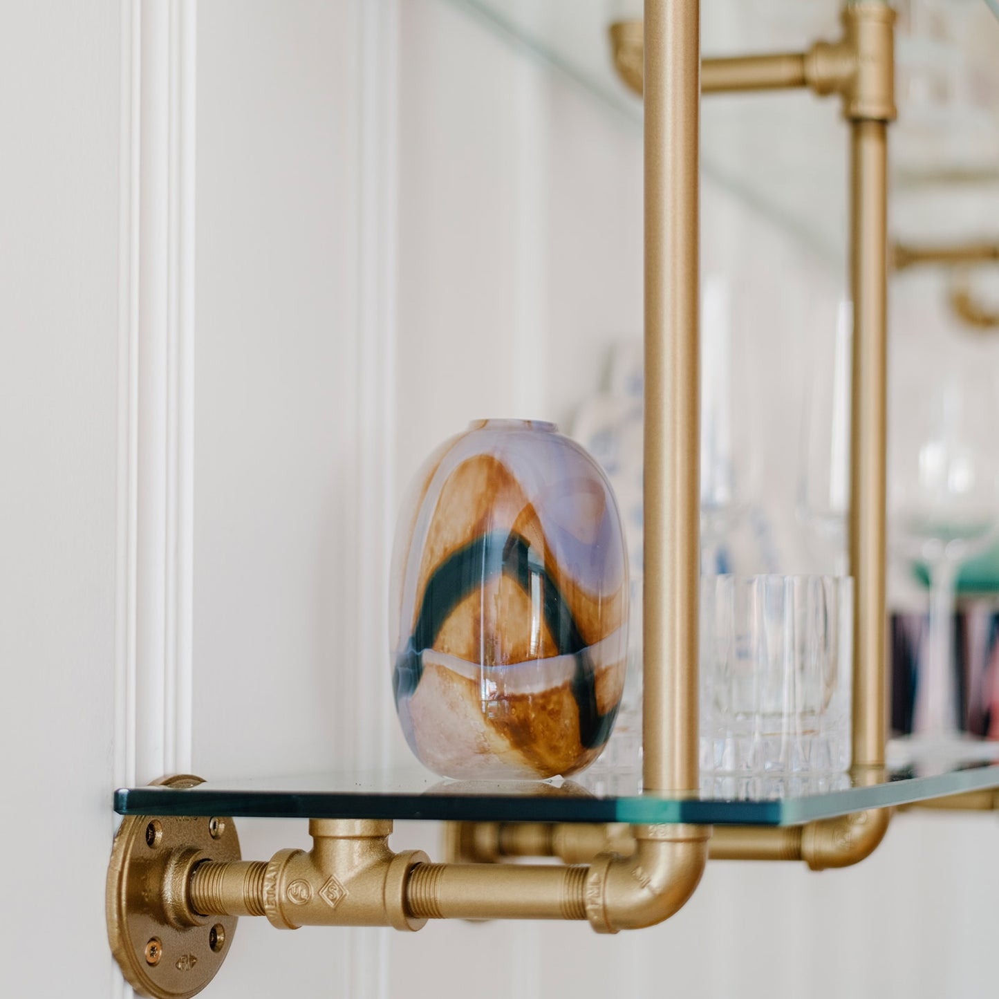 close up of kitchen and bar wall mounted shelving with brass plated pipes and glass shelves | Soil & Oak