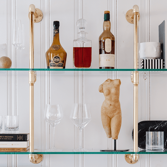 close up photo of brass plated pipes and glass shelves on a white wall | Soil & Oak 