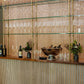 Soil & Oak custom built bar setup with wine glasses, bottles, and decor against a striped wall.