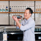 Bartender holding a cocktail shaker with custom Soil & Oak shelves in the background.