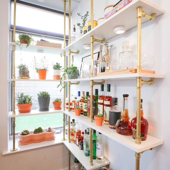 white painted common board shelves with brass plated pipes