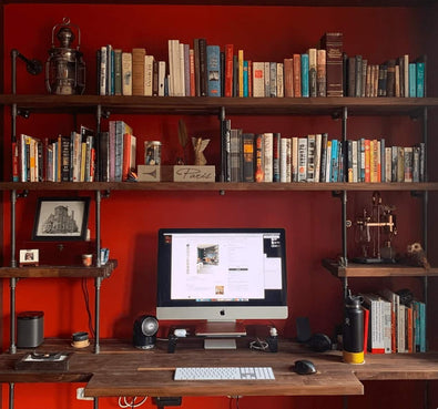 custom built-in desk and wall mounted shelves unit with black piping and wood shelves in a red room