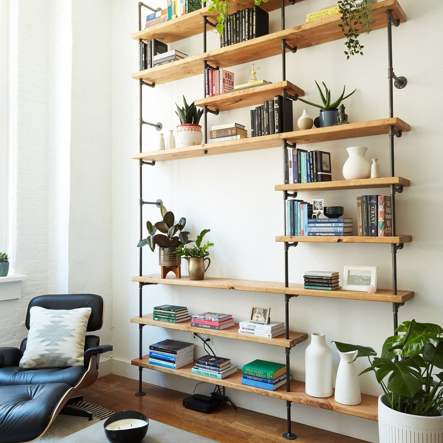custom bookshelf with back pipes and oak shelves in apartment living room | Soil & Oak 
