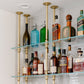 close up photo soil & oak ceiling mounted bar and kitchen shelving with brass plated pipes and glass shelves in white tiled bar