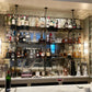 Counter to ceiling shelving with black pipes and glass shelves in bar | Soil & Oak 