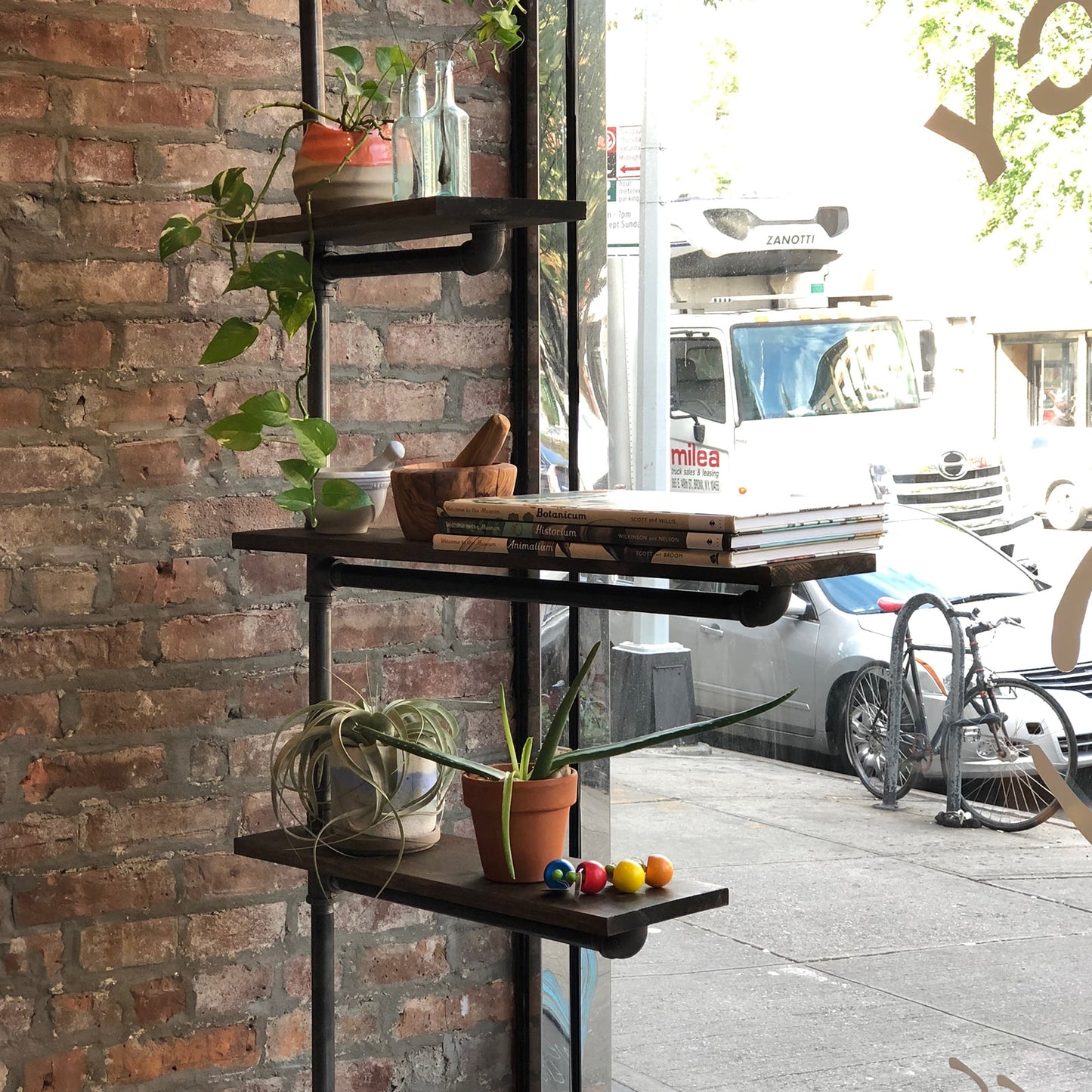 custom bookshelf with black pipes and dark stained wood shelves used in a brick and mortar display | Soil & Oak 