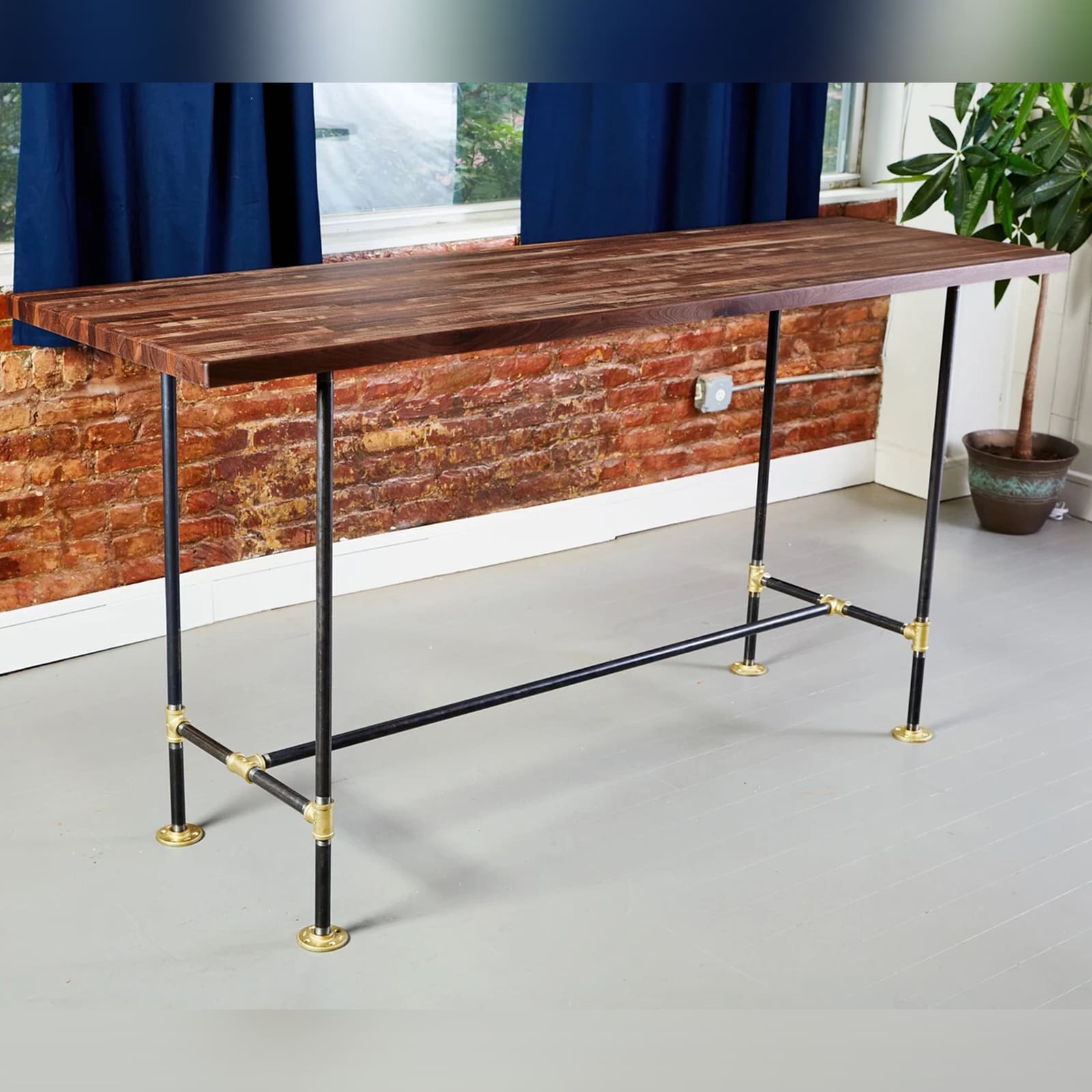soil & oak standalone desk with black pipe legs and brass fittings and an walnut butcher block table top with leg rest
